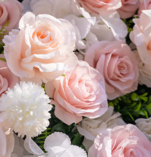 Close-up of pale pink and white roses with white and green floral accents.