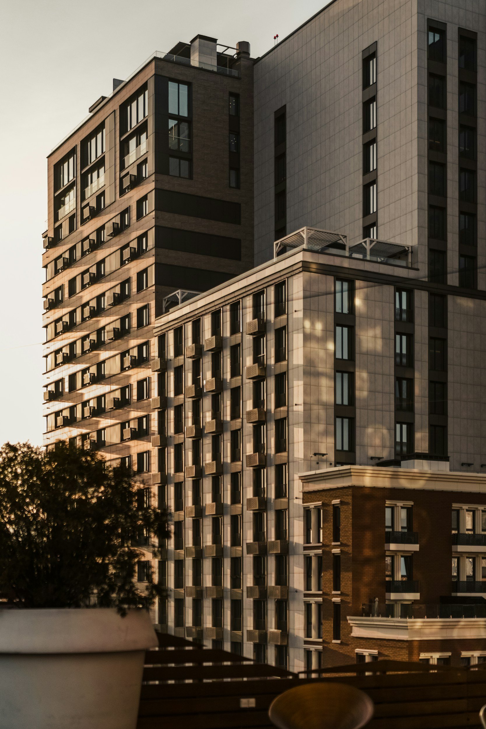 A modern multi-story building with numerous windows and balconies, filmed during sunset with the sky dimly lit.