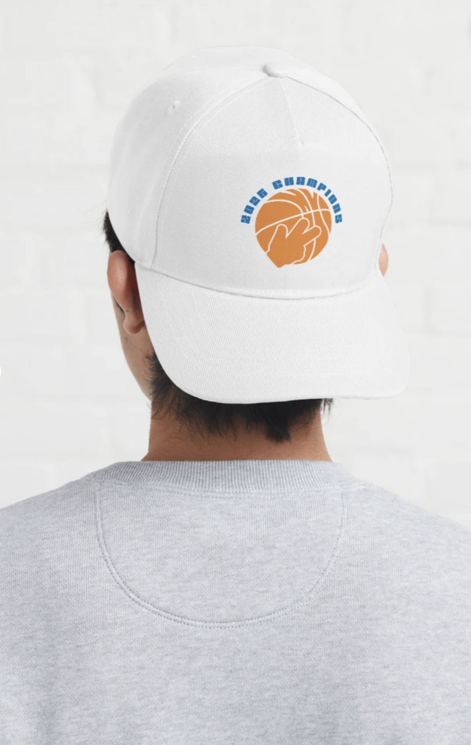 White cap with a logo featuring a hand holding a basketball and the text '2023 Championships' in blue, worn by a person with dark hair and a gray shirt against a white background.