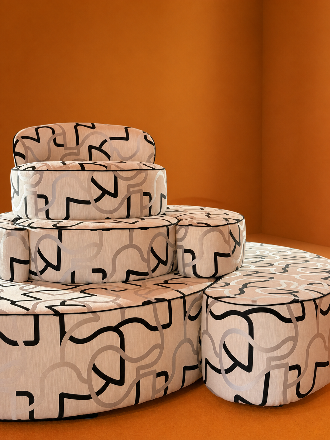 Stacked round tables with abstract black and white line patterns on a peach-colored wood surface, against an orange background.