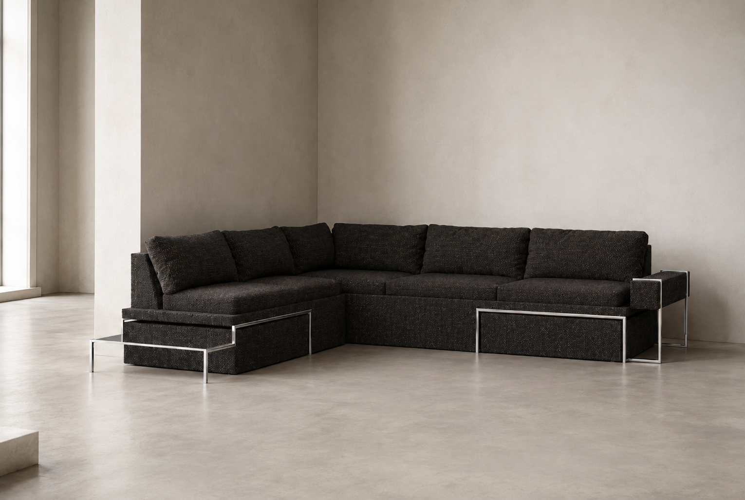Modern black sectional sofa with metal frame legs in a minimalist room with light-colored concrete floor and plain wall.