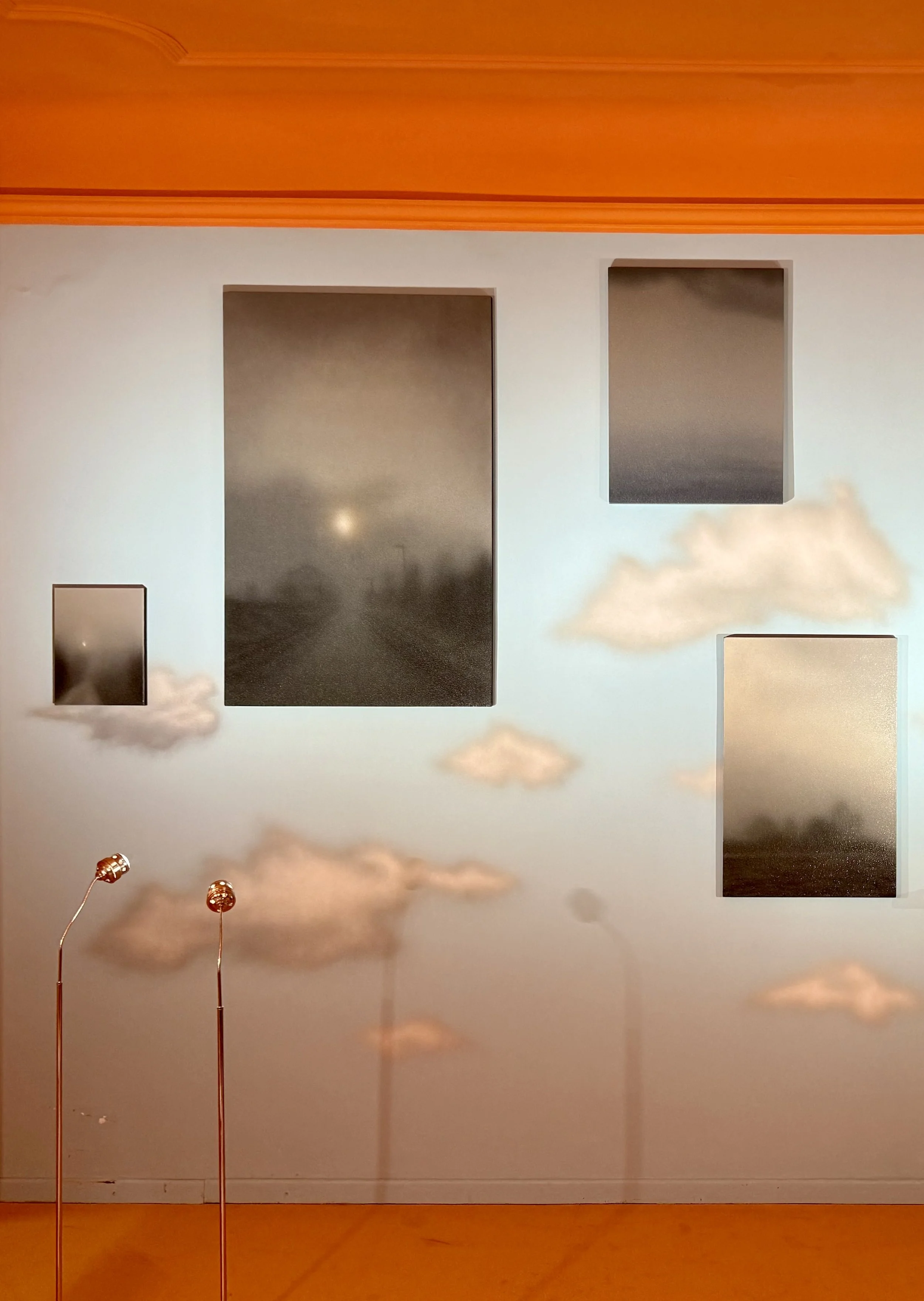Clouds and sky reflected on wall-mounted mirrors and water bottles on a table.