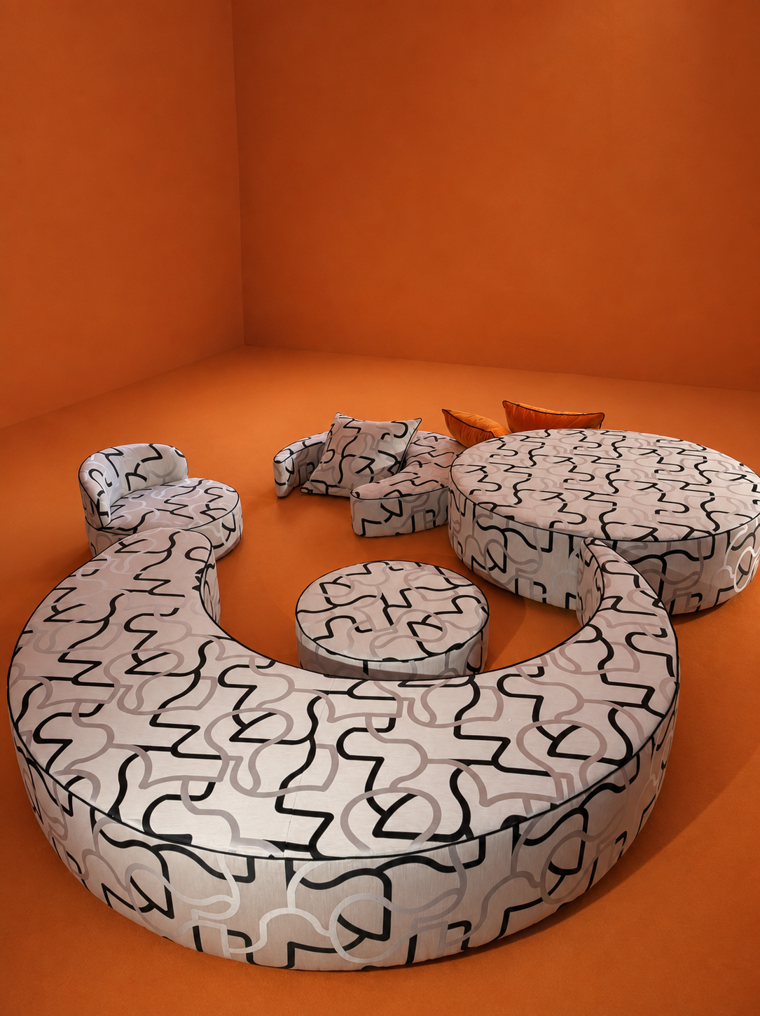A contemporary room with bright orange walls and floor, featuring a circular sofa with black and white abstract pattern, matching round ottoman, and several cushions including two orange ones.