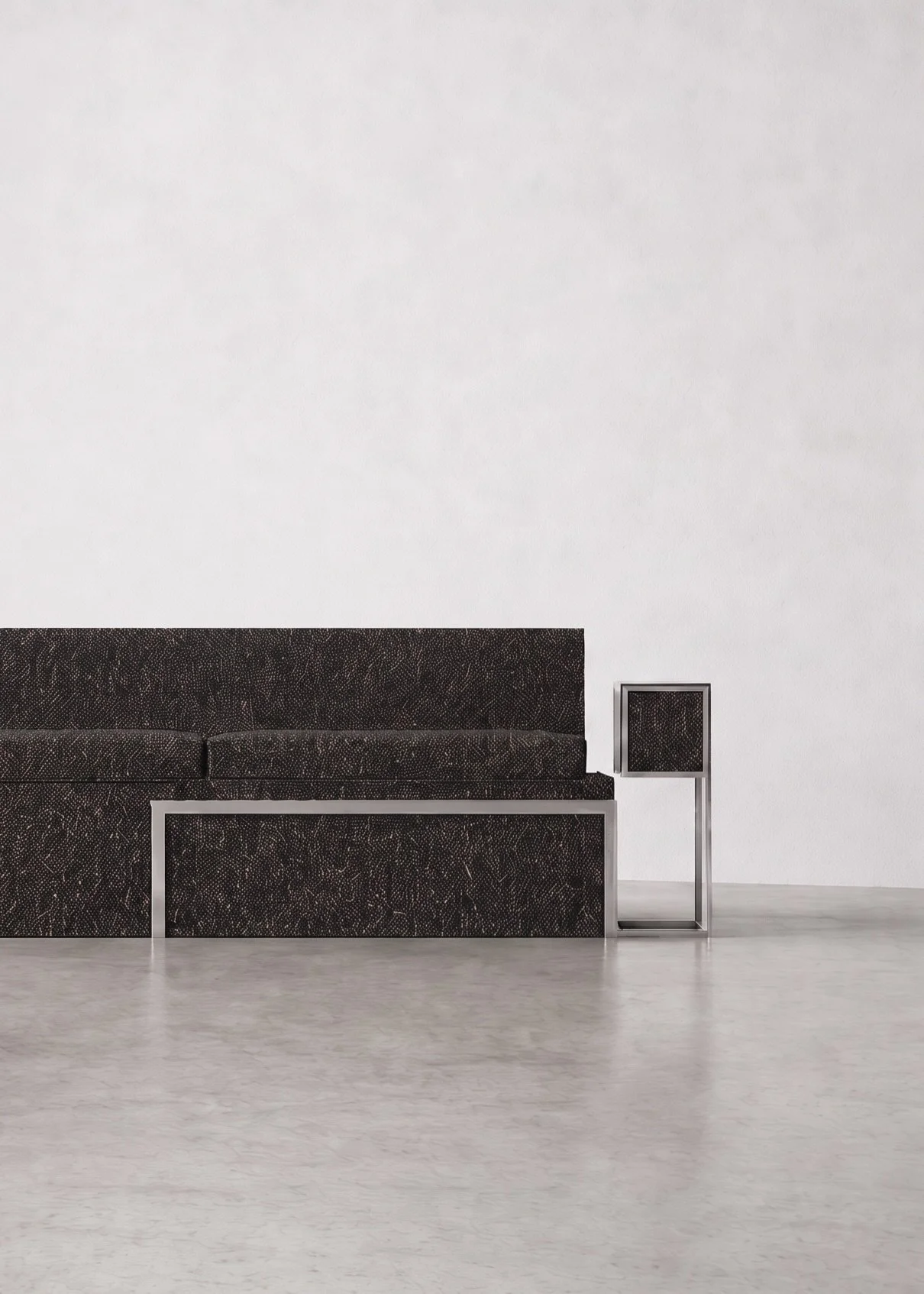 Minimalist interior with a black textured sofa, a matching black textured side table, and a white wall background.