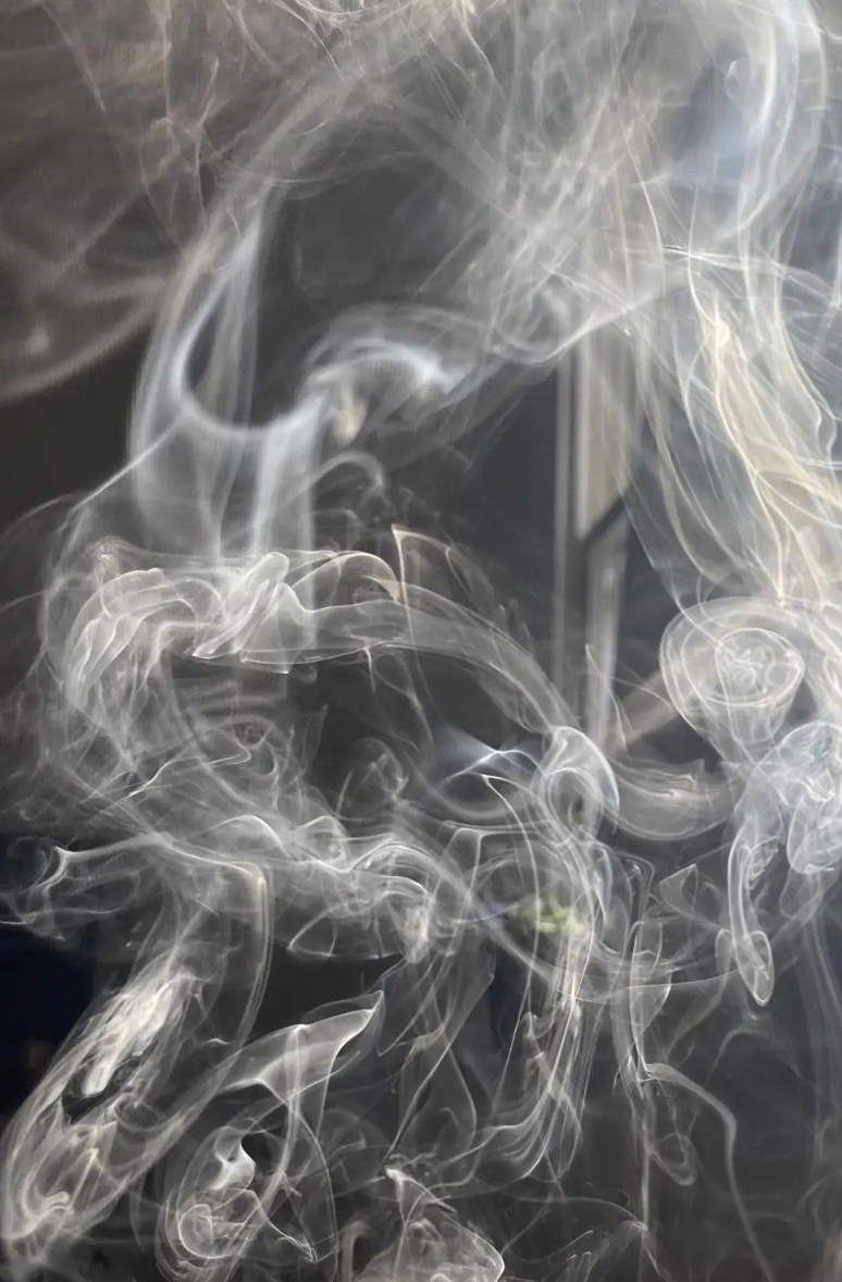 Close-up of translucent white smoke wisps swirling against a dark background