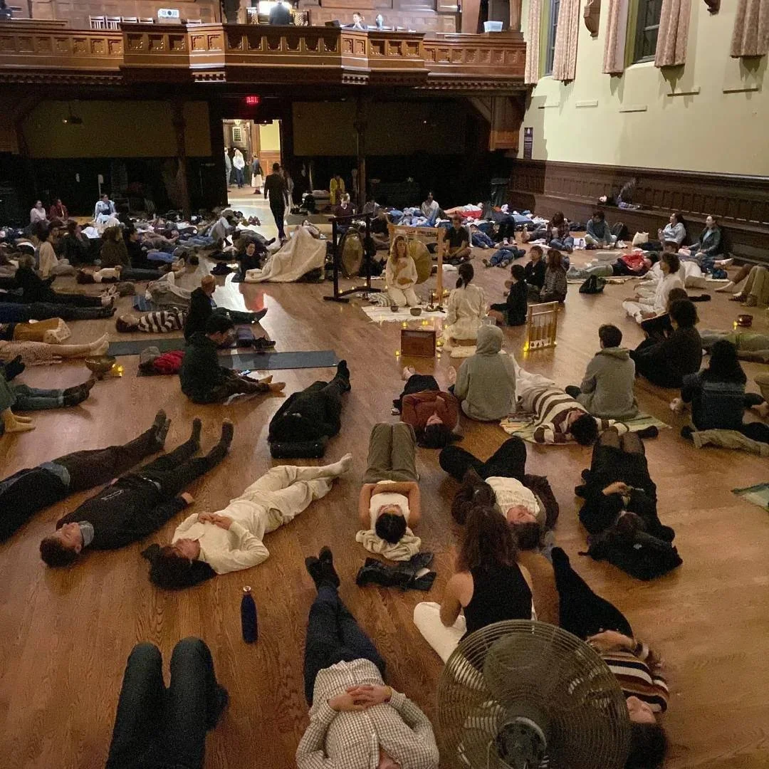 Large group of people lying and sitting on the floor during a meditation or relaxation session in an ornate historic hall