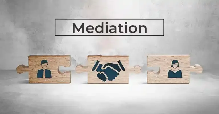 Three wooden puzzle pieces with icons of a person, a handshake, and another person, placed beneath a sign that reads 'Mediation'.