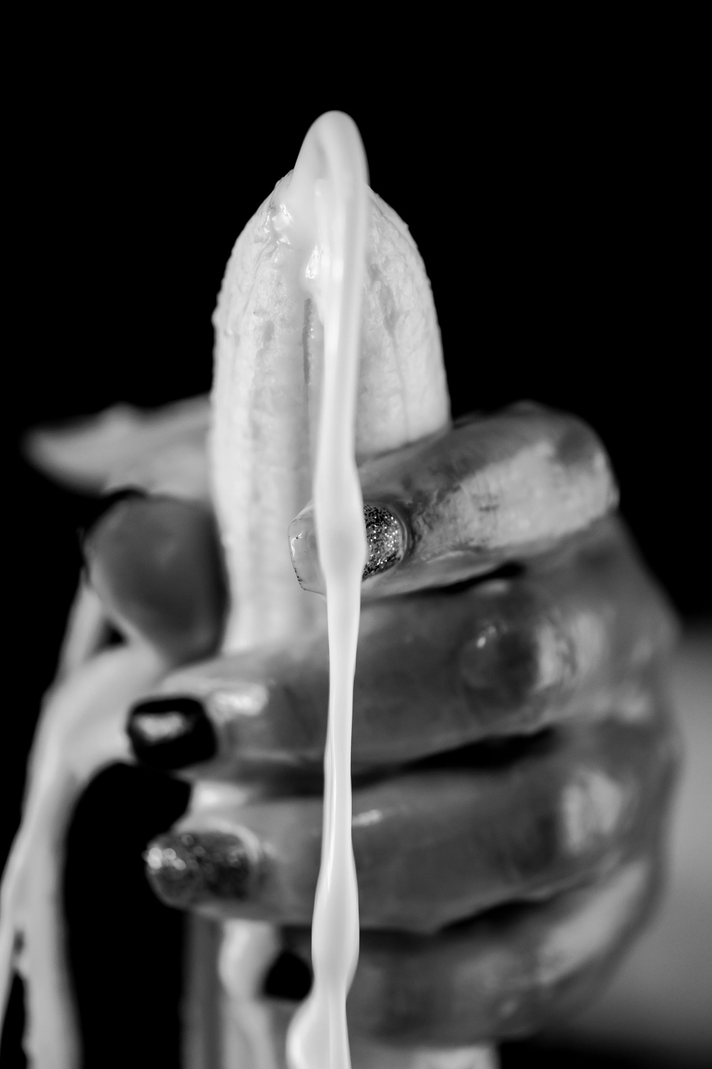 A close-up black and white photo of a human hand with the index finger sticking out, with a stream of white flowing down from the top of the finger against a black background.