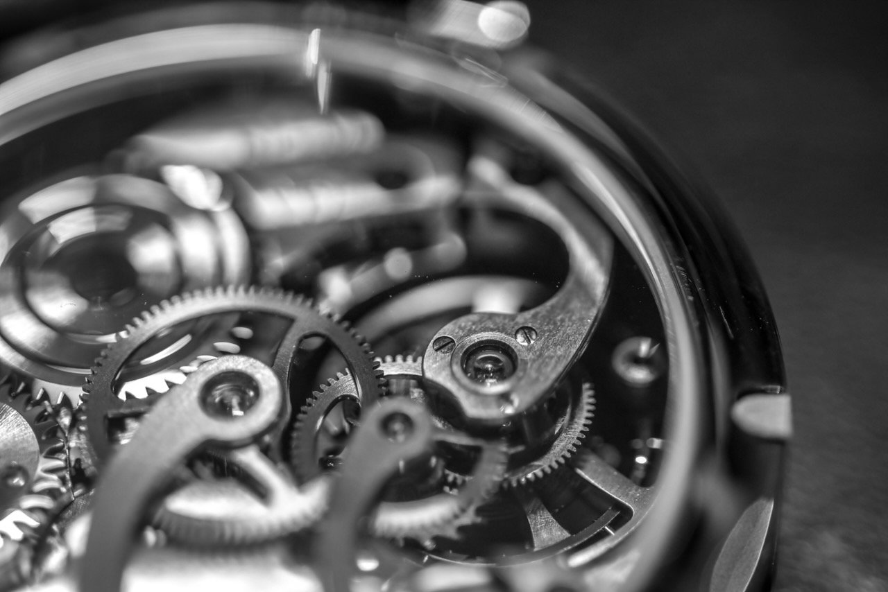 Close-up of the intricate gears and inner mechanisms of a mechanical watch in black and white.