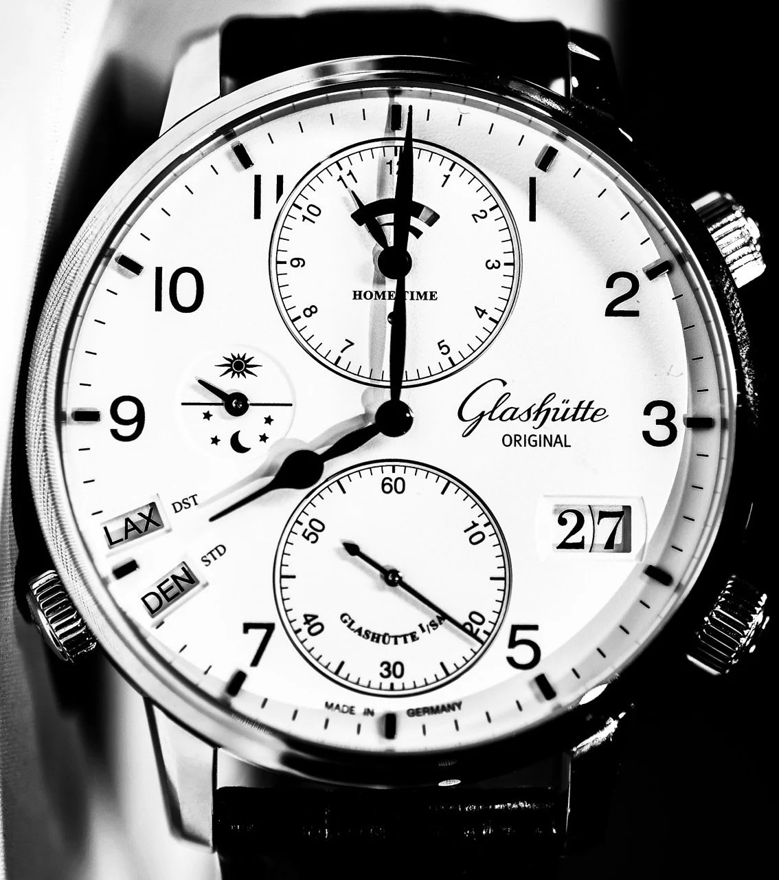 A close-up of a Glashütte Original wristwatch showing the time as 8:00 with additional dials and features, including a date display of 27.