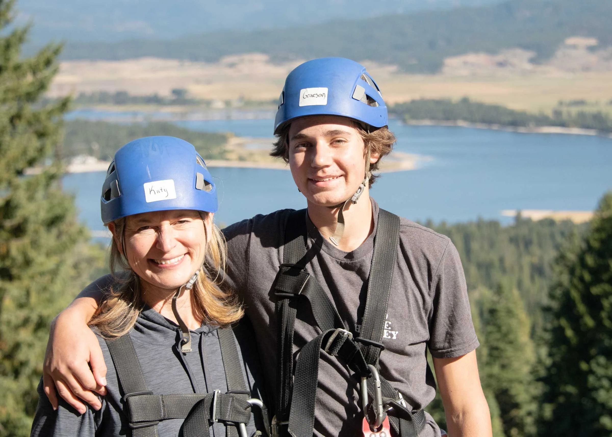 Mom and son with outdoor safety gear standing in front of scenic lake