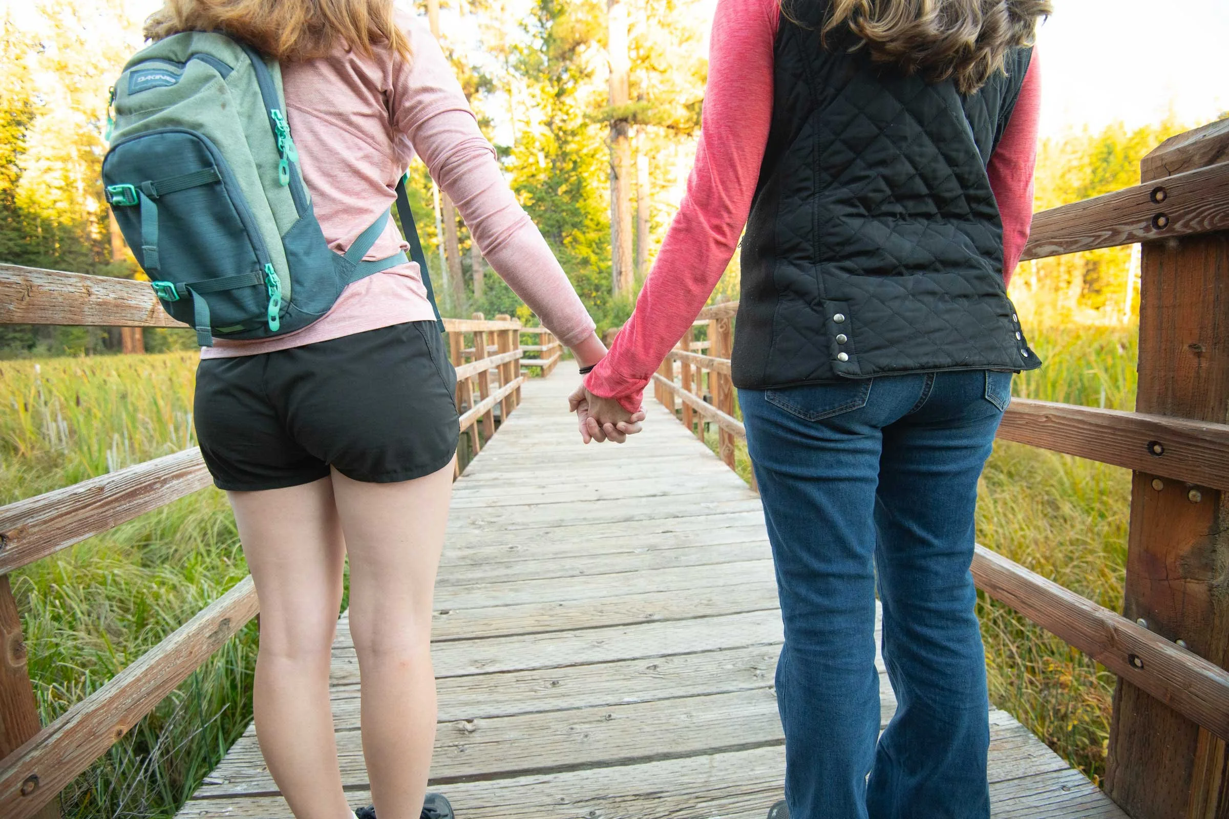 Mom and daughter holding hands on a bridge