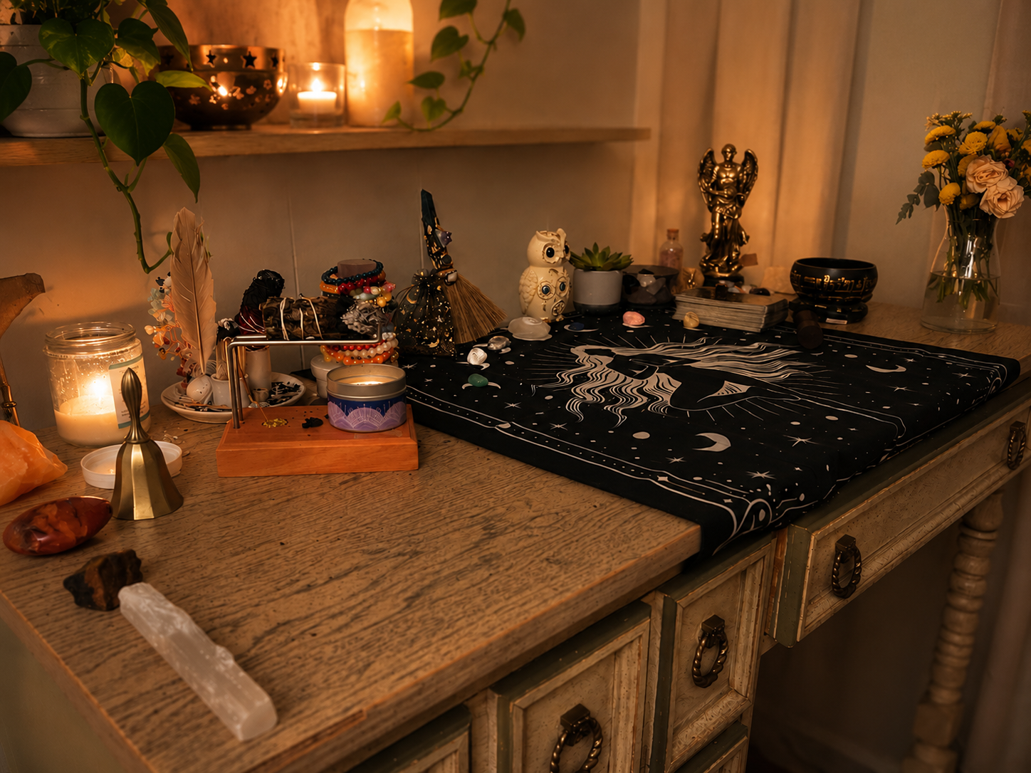 A wooden table with various spiritual and decorative objects, including candles, crystals, statues, and jewelry, is illuminated by warm candlelight.