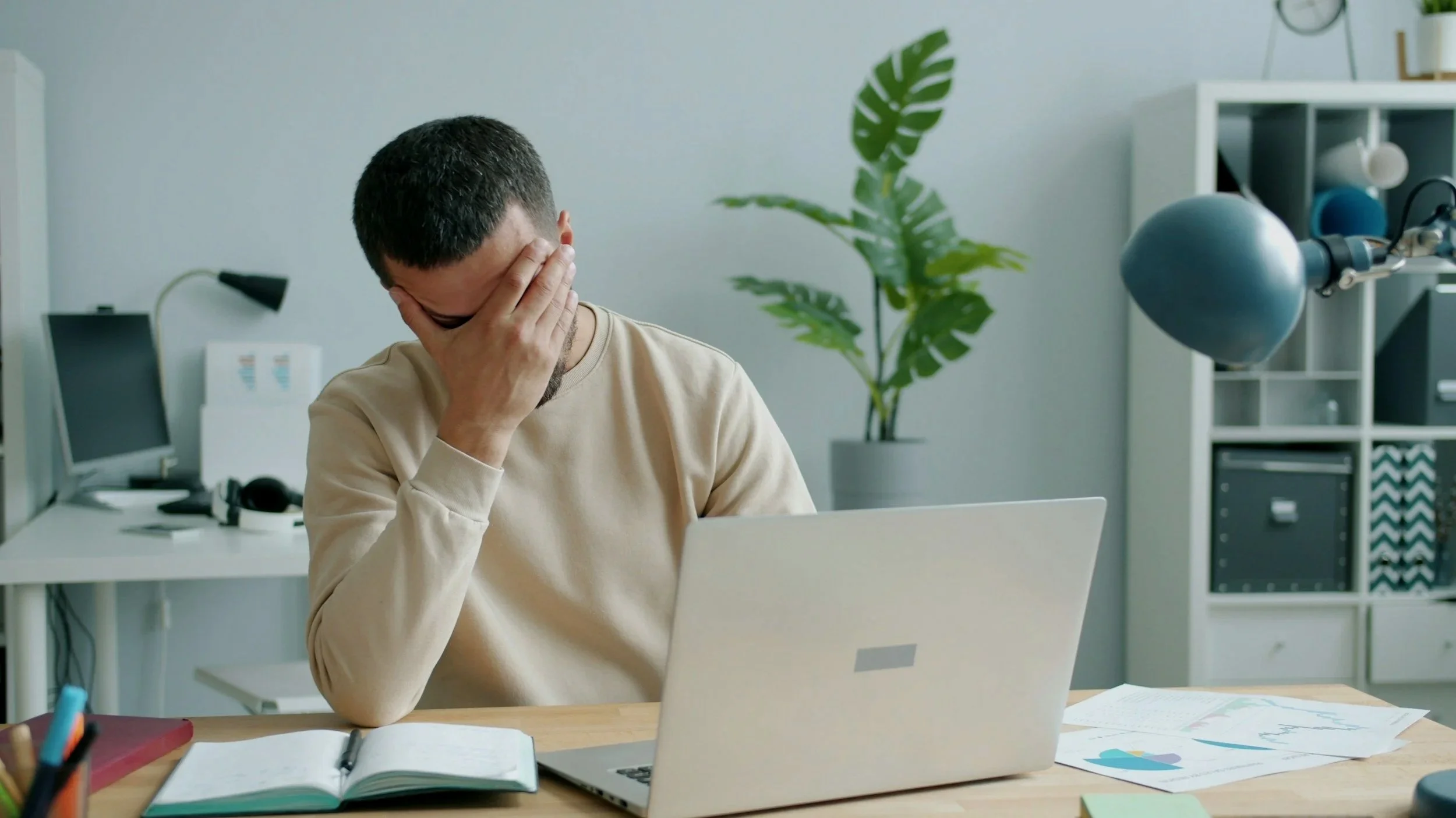 man with hands on temples at desk headache