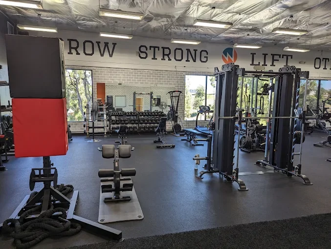 Motivating personal training space in La Mesa featuring 'ROW' and 'STRONG' wall graphics alongside extensive gym equipment.