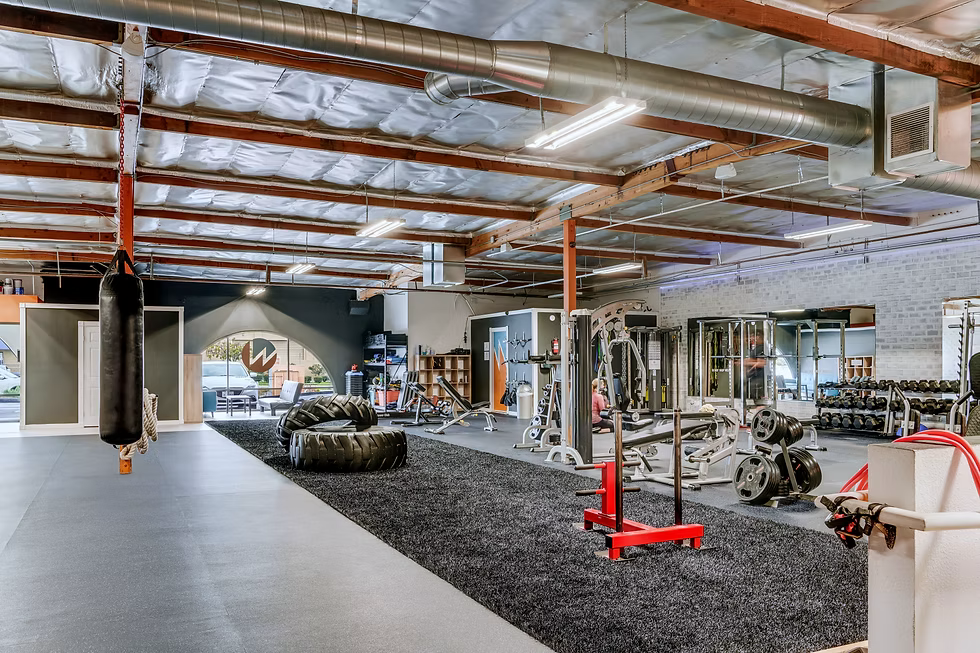 Fully equipped gym floor in Bay Park, San Diego for strength and conditioning, showing exercise mats, weight machines, and a punching bag.