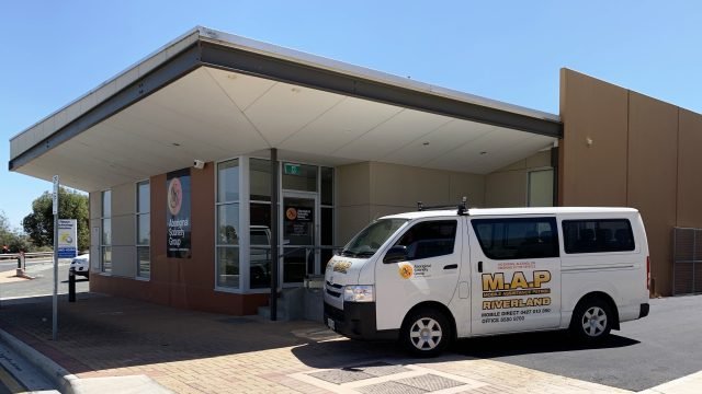 A building with a white van parked in front, which has the logo and text for M.A.P. Riverside Land on its side.