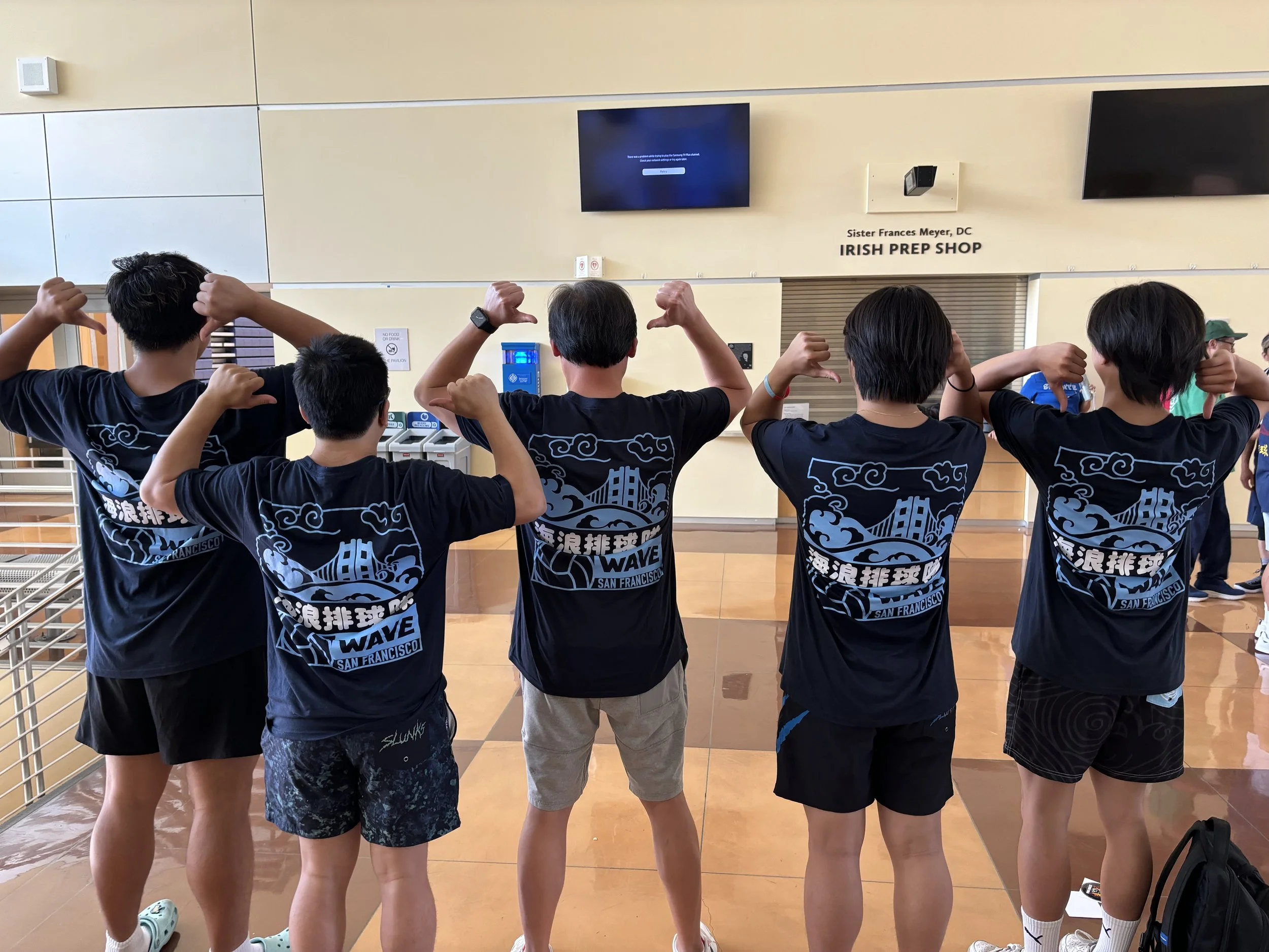 Group of young people standing in a row, flexing their arms in front of a sign that says "Irish Prep Shop" at Sister Frances Meyer, DC.