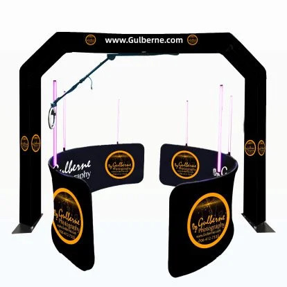Photo of a photo booth setup with black side panels and a black archway, featuring the website www.Gulberne.com and photography branding in orange and white, with purple LED lighting accents.