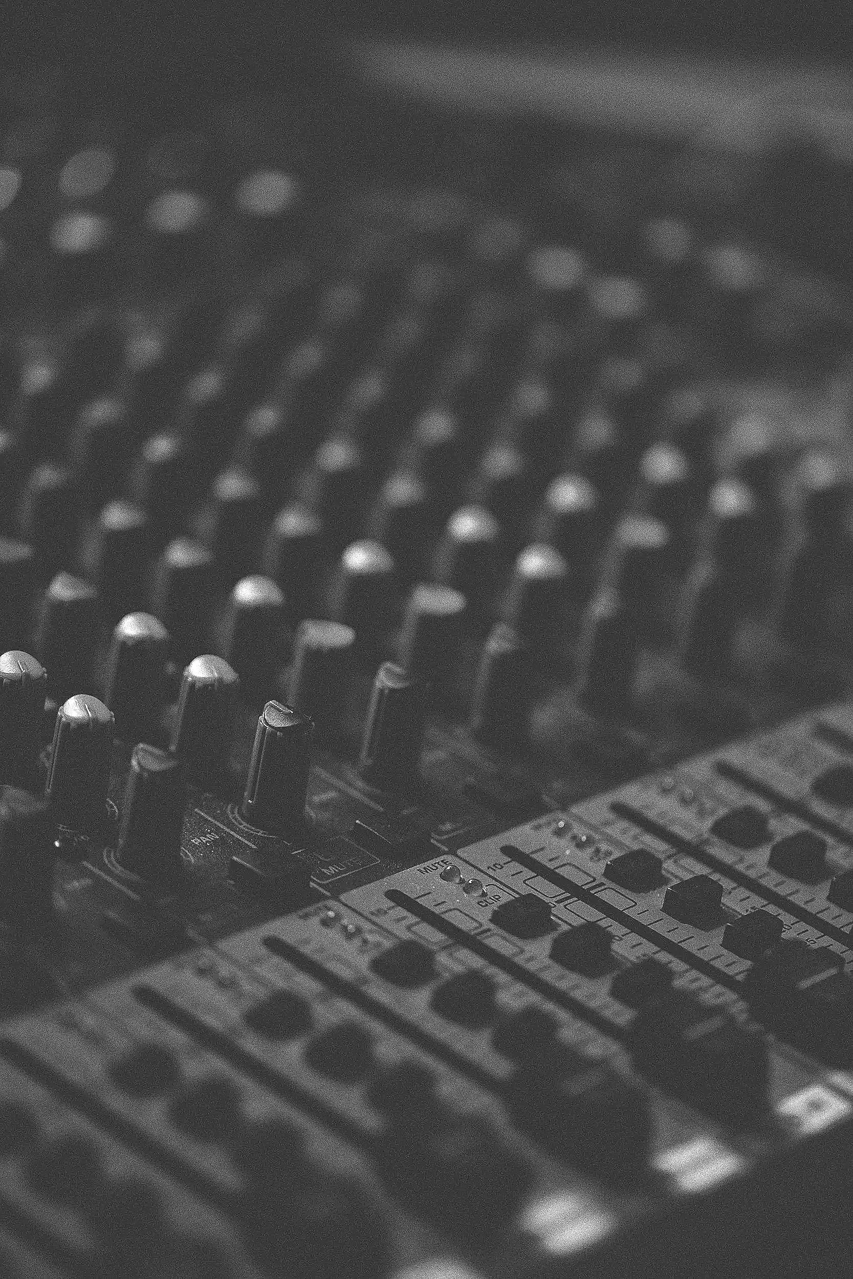 Close-up of a professional audio mixing console with various knobs, sliders, and buttons for sound control.