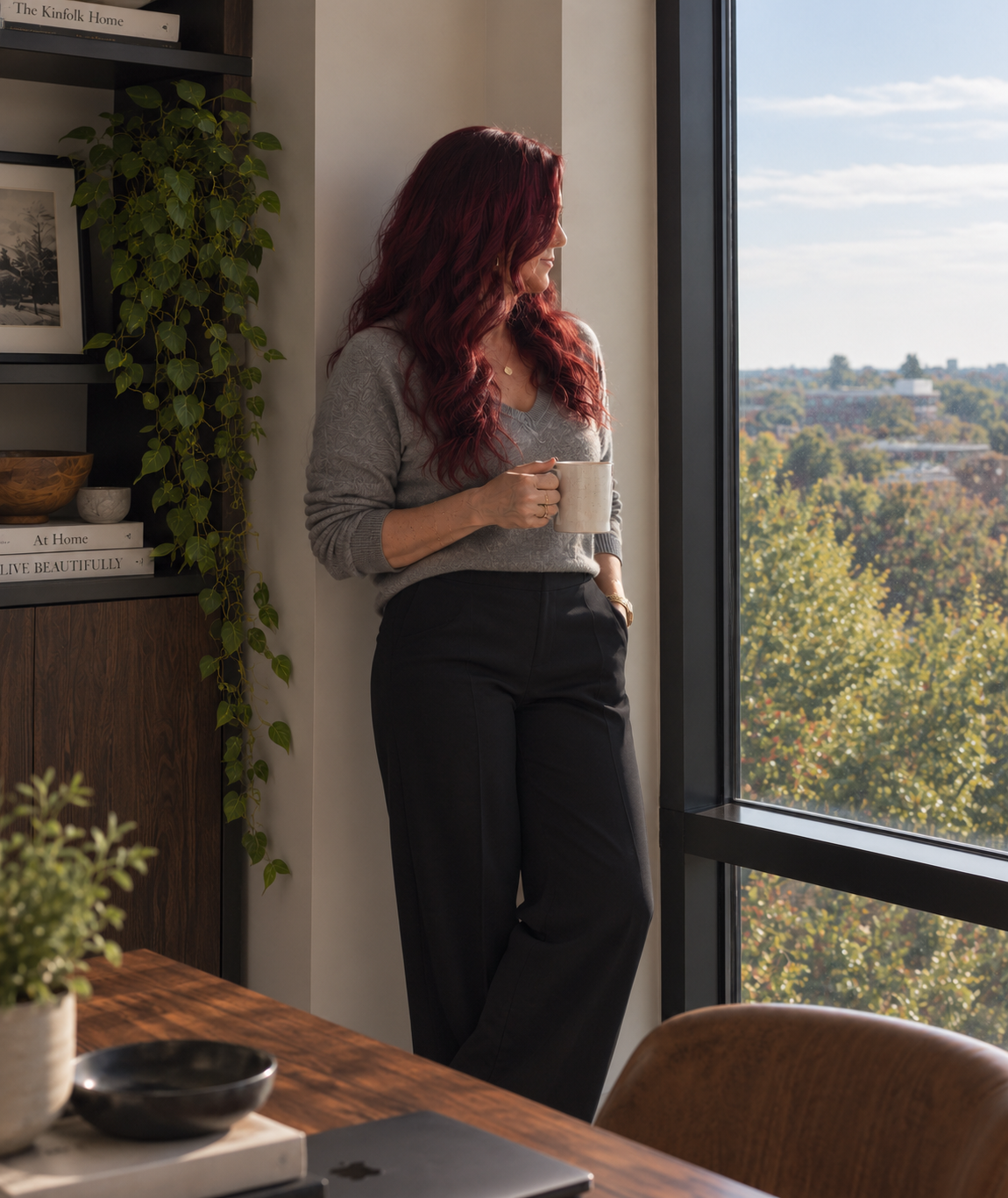 Dr. Melissa Bartnick, therapist for professionals and leaders, standing by a window with a cup of coffee.
