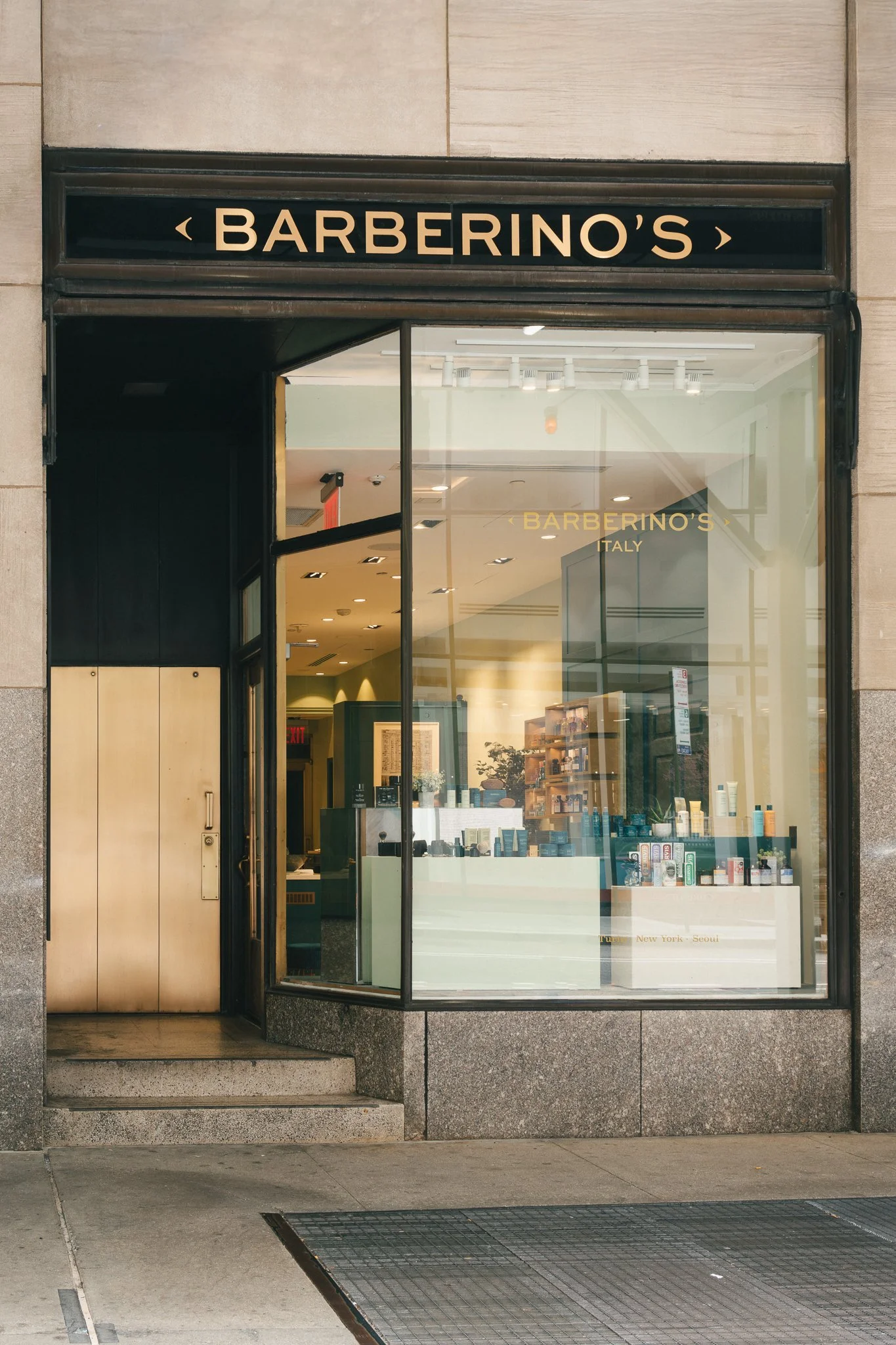 The storefront of Barberino's, an Italian brand, with a large glass window displaying various hair and skincare products, and signage indicating locations in New York and Seoul.