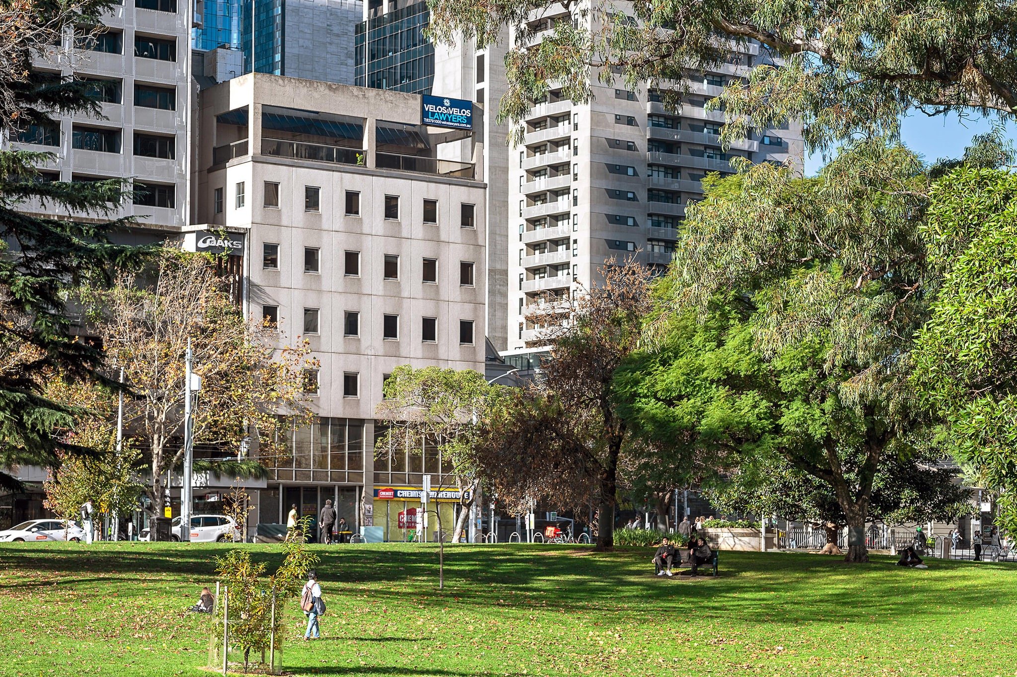 External view of Flagstaff Mediation Centre, at corner William and La Trobe Streets Melbourne. Overlooking Melbourne's Flagstaff Gardens - a large city park with green grass and trees in the foreground, and tall office buildings in the background.