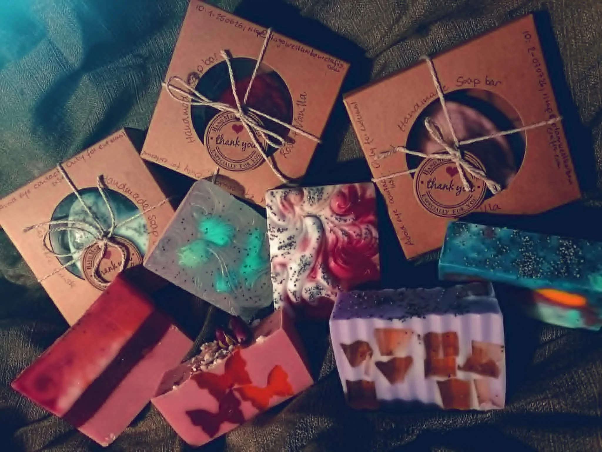 A collection of gift cards and small wrapped presents with various designs, including one with a selfie of a young girl on a pink background, and others with images of makeup products, a bear, and colorful patterns, lying on a dark surface.