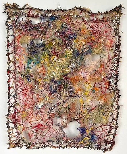 Mixed media abstract art piece with a web-like structure in red, yellow, and metallic colors, bordered by a dark, vine-like frame.