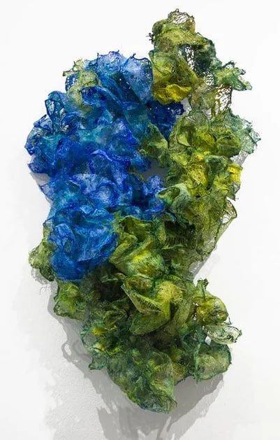 Abstract glass sculpture with blue and green colors and ruffled textures.