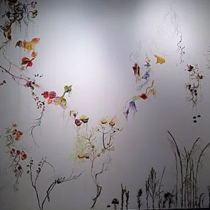Art installation of colorful butterflies and plants on a white wall.