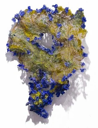 A decorative wreath made of twigs decorated with blue and yellow flowers or leaves.
