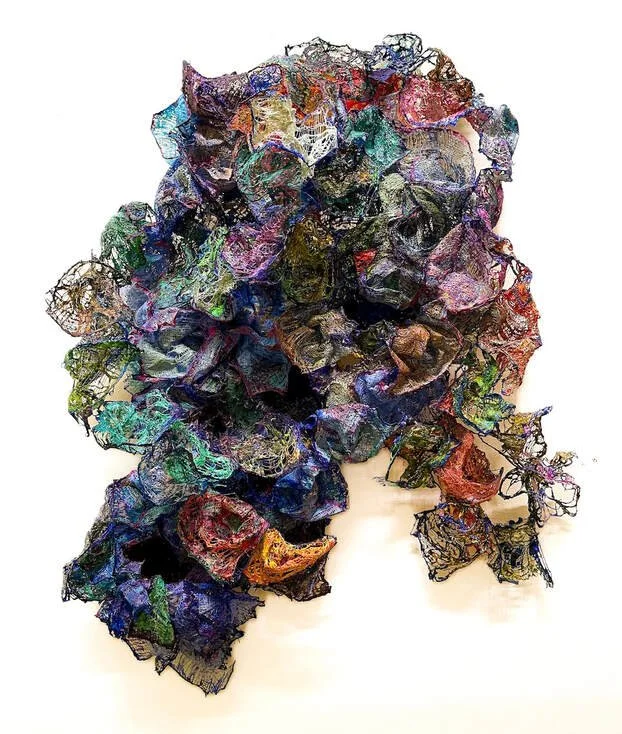 Mixed-media abstract sculpture resembling the shape of a dog's head with colorful, textured layers.