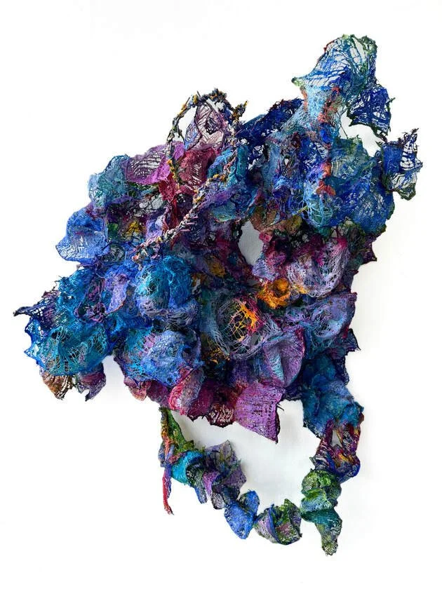 Colorful abstract mixed-media sculpture with layered, textured fabric and wire elements.