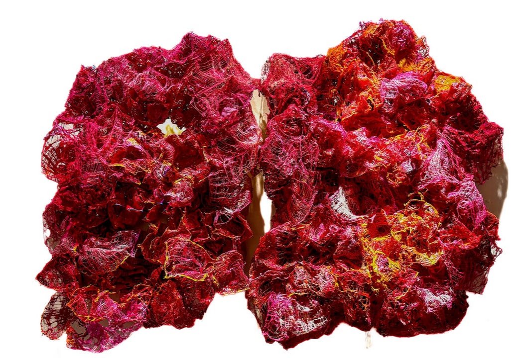 A pair of artificial lungs used for medical training, made of red, yellow, and purple mesh material to mimic lung tissue.