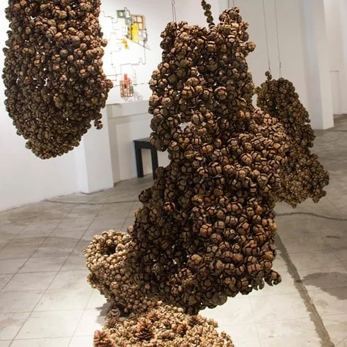 Sculpture resembling a cluster of pine cones or natural organic forms in an art gallery.