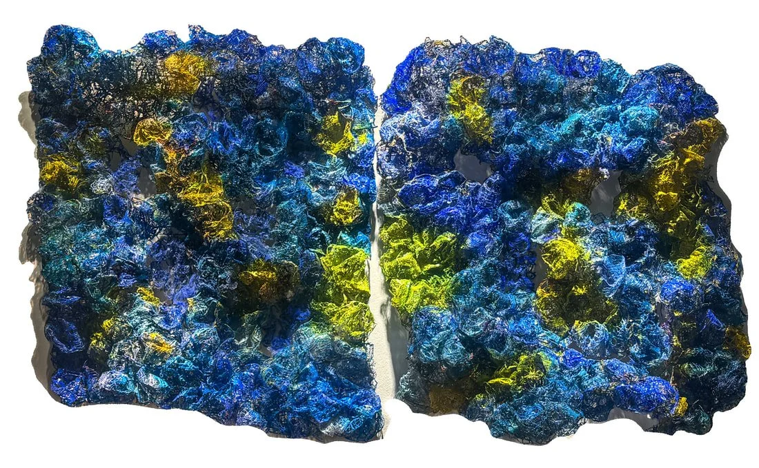 Close-up of two pieces of textured glass with blue, yellow, and black colors.