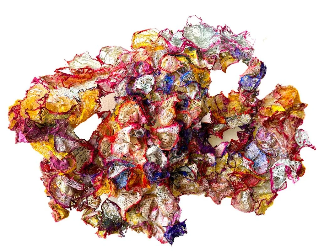 Colorful, abstract sculpture made of crumpled, textured fabric or paper on a white background.