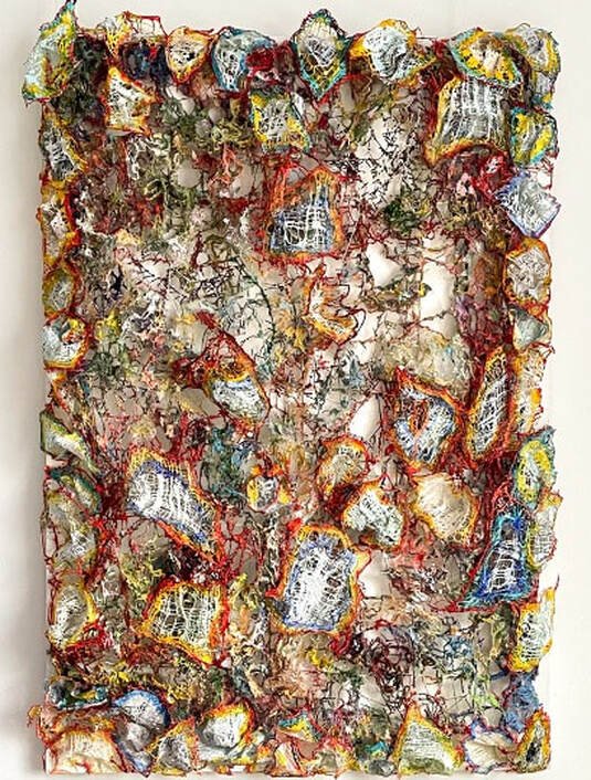 Abstract mixed media artwork featuring irregular, layered fragments of colorful materials with textured, thread-like details and a central face outline.