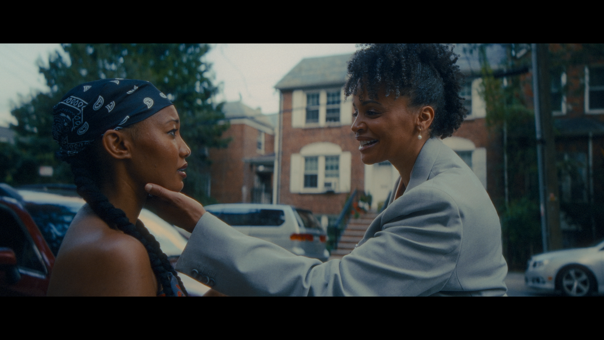 Annette grabbing Elle's face while standing outside in a neighborhood