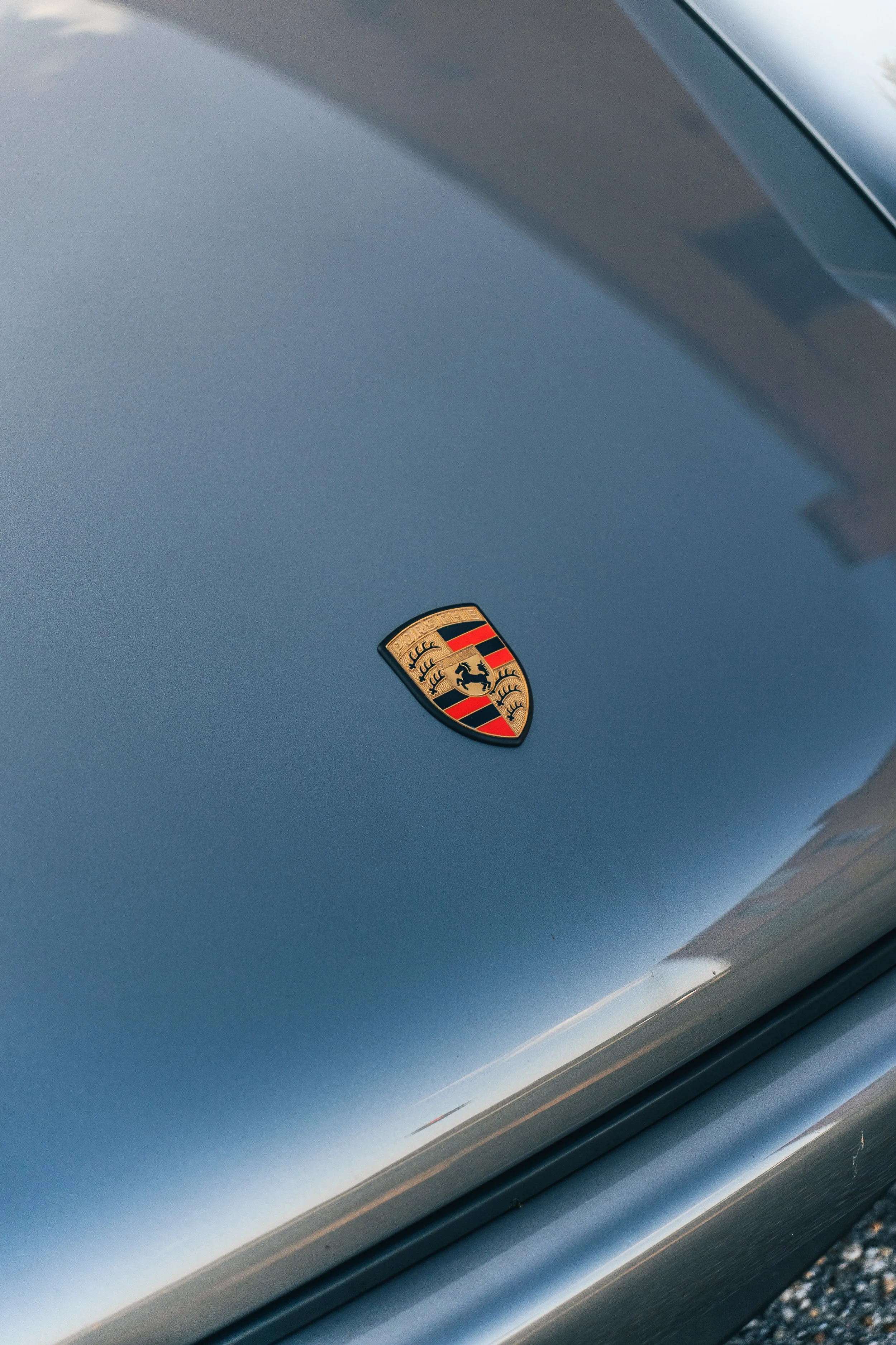 Close-up of a gray Singer Porsche 911 with a Porsche emblem on the hood.
