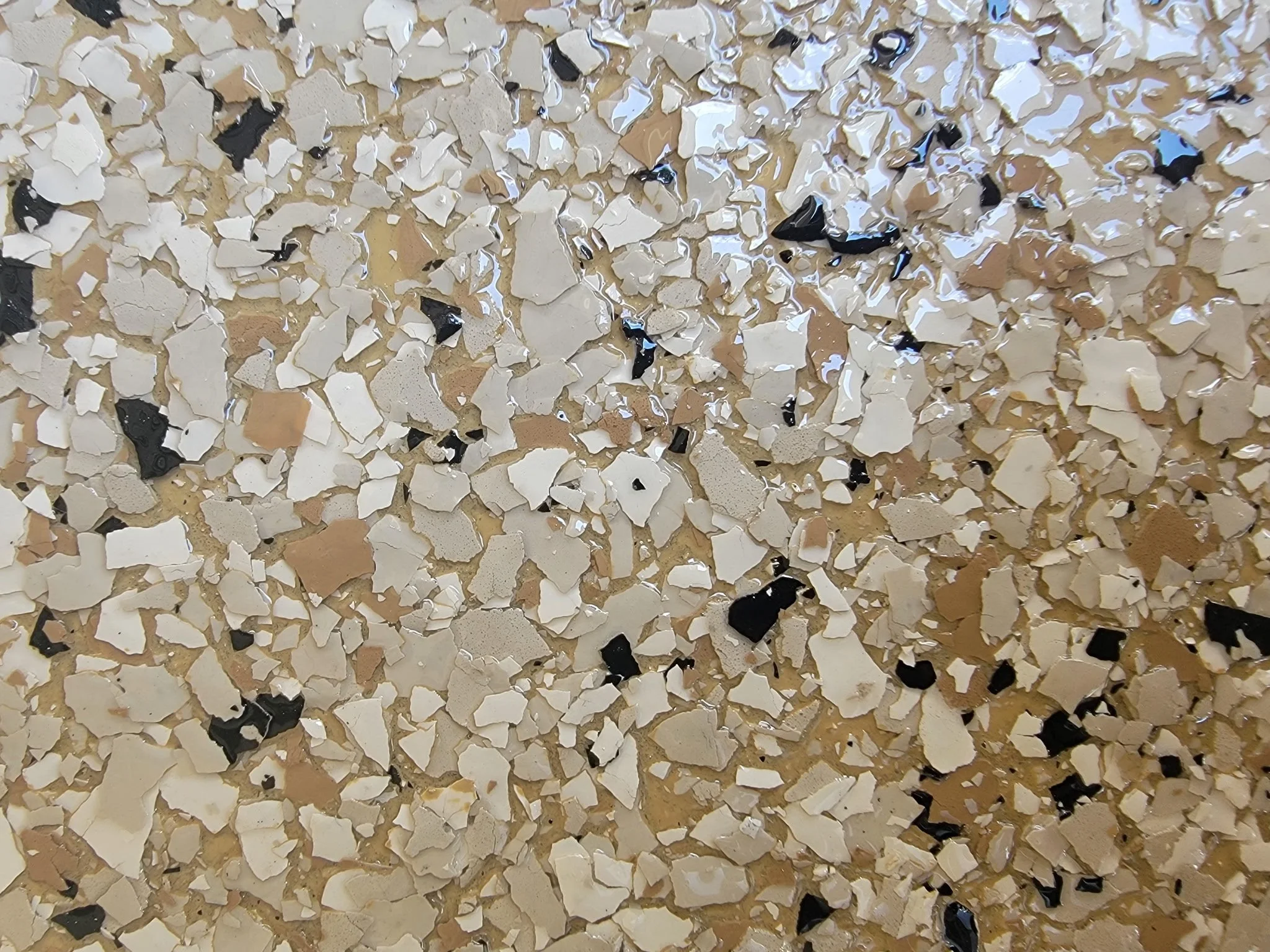 Close-up of a textured surface with small irregular chalky white, beige, black, and shiny black pieces.