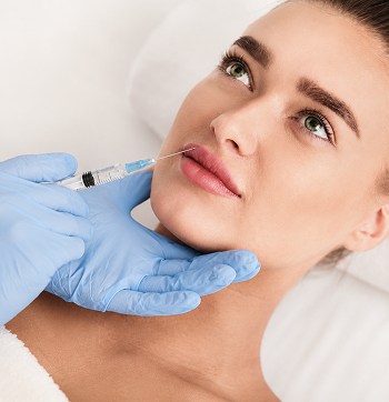 A woman receiving a cosmetic injection in her face from a healthcare professional wearing blue gloves.