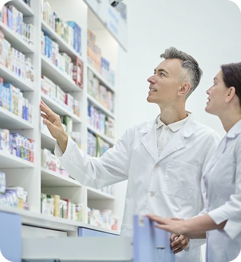 Two pharmacists or pharmacy technicians working in a pharmacy, selecting medication from shelves.