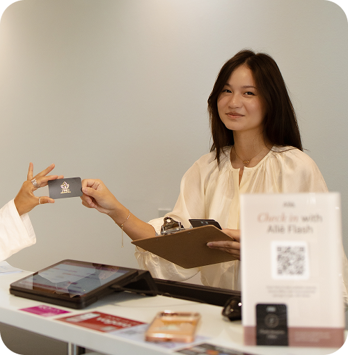 A woman at a reception desk handing over a card to another person.