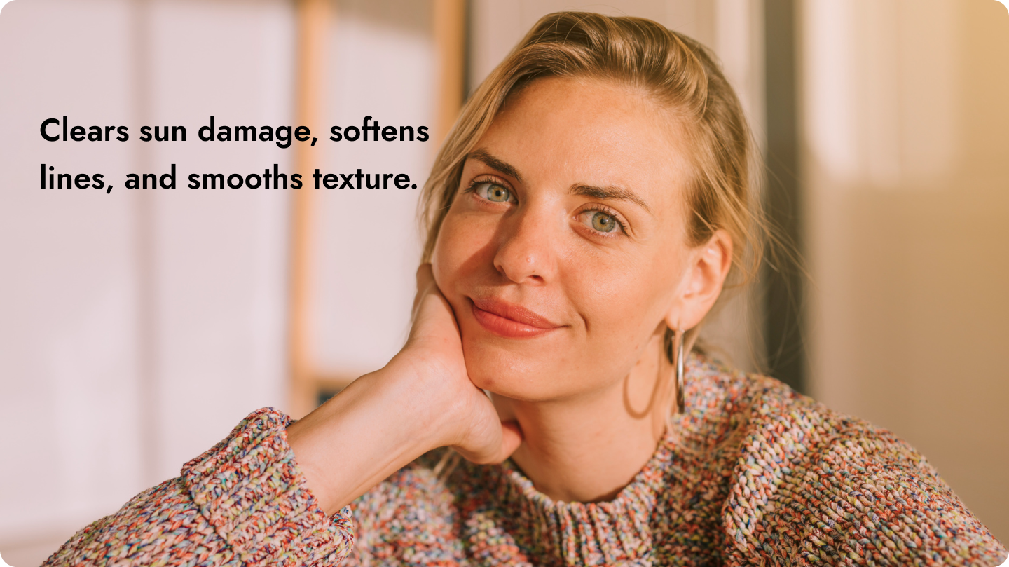 A woman resting her chin on her hand and smiling gently, with a background of warm indoor lighting.