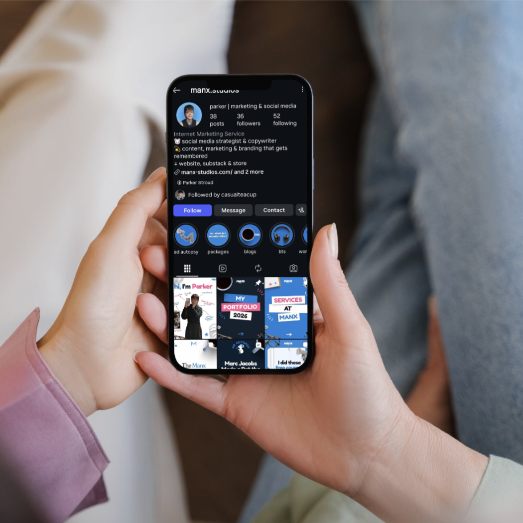 Close-up of a person holding a smartphone displaying an Instagram profile for 'manx.studios' with content related to marketing and social media, and profile highlights.