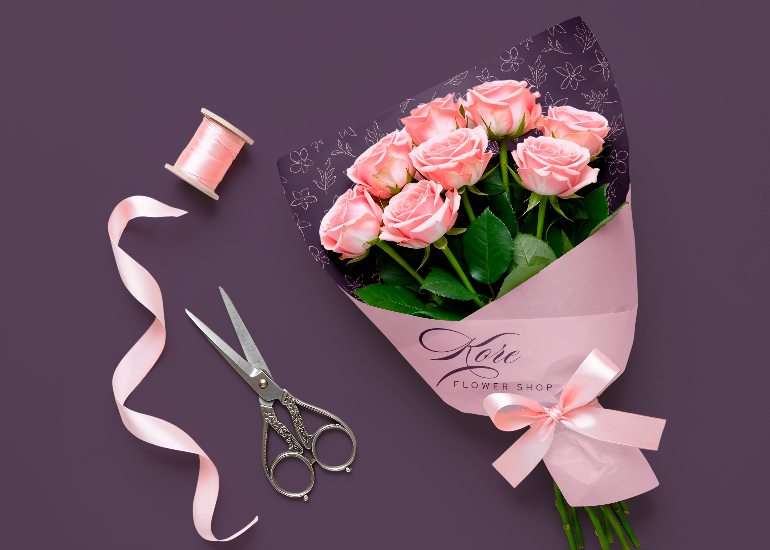 A bouquet of light pink roses wrapped in pink floral paper with the word 'Love' written on it, pink ribbon, silver scissors, and a spool of pink ribbon on a purple background.