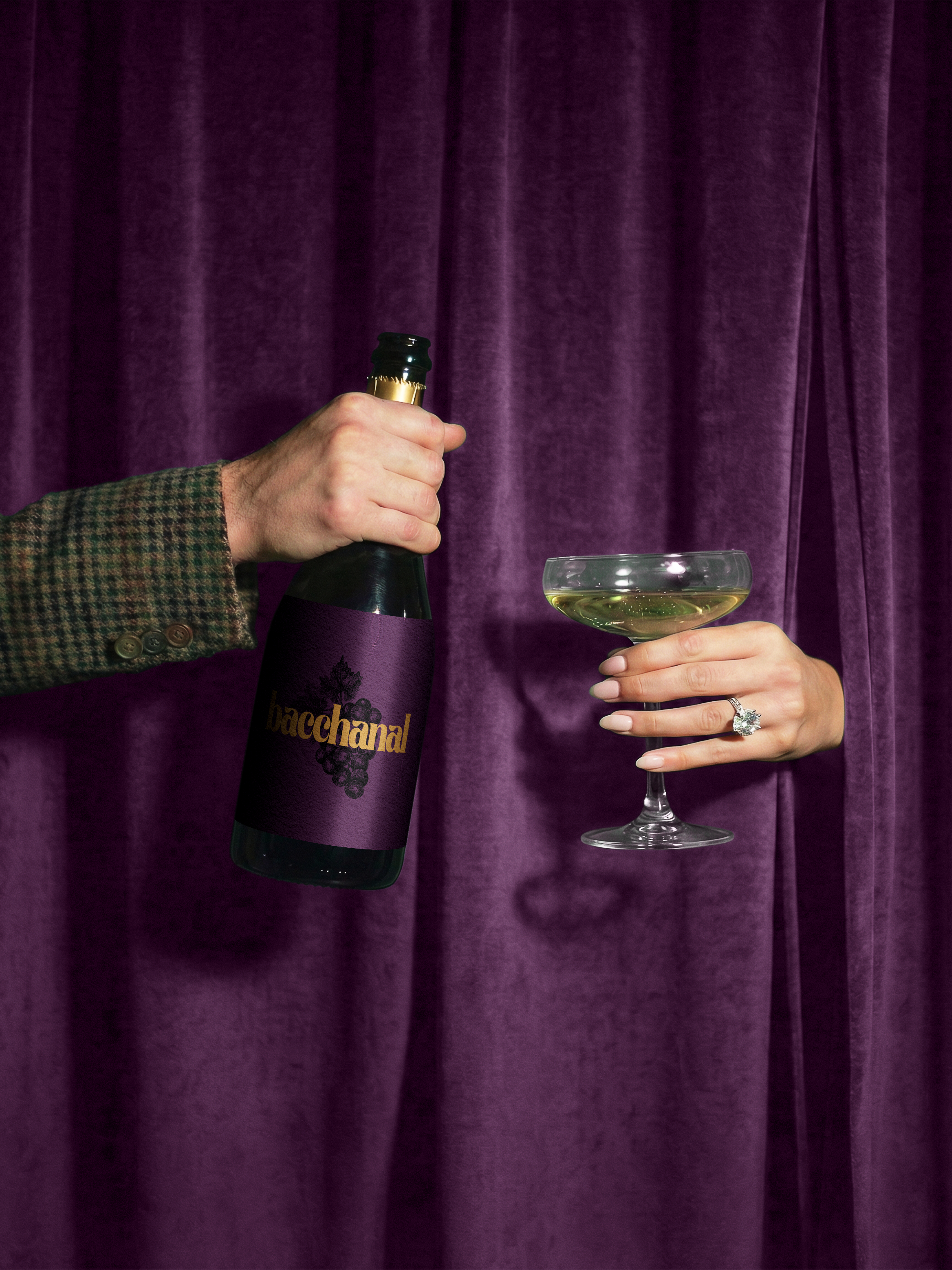 A person in a patterned jacket holding a bottle of Baccanal sparkling wine with purple label, and another person holding a cocktail glass with pale yellow liquid, against a backdrop of purple velvet curtain.