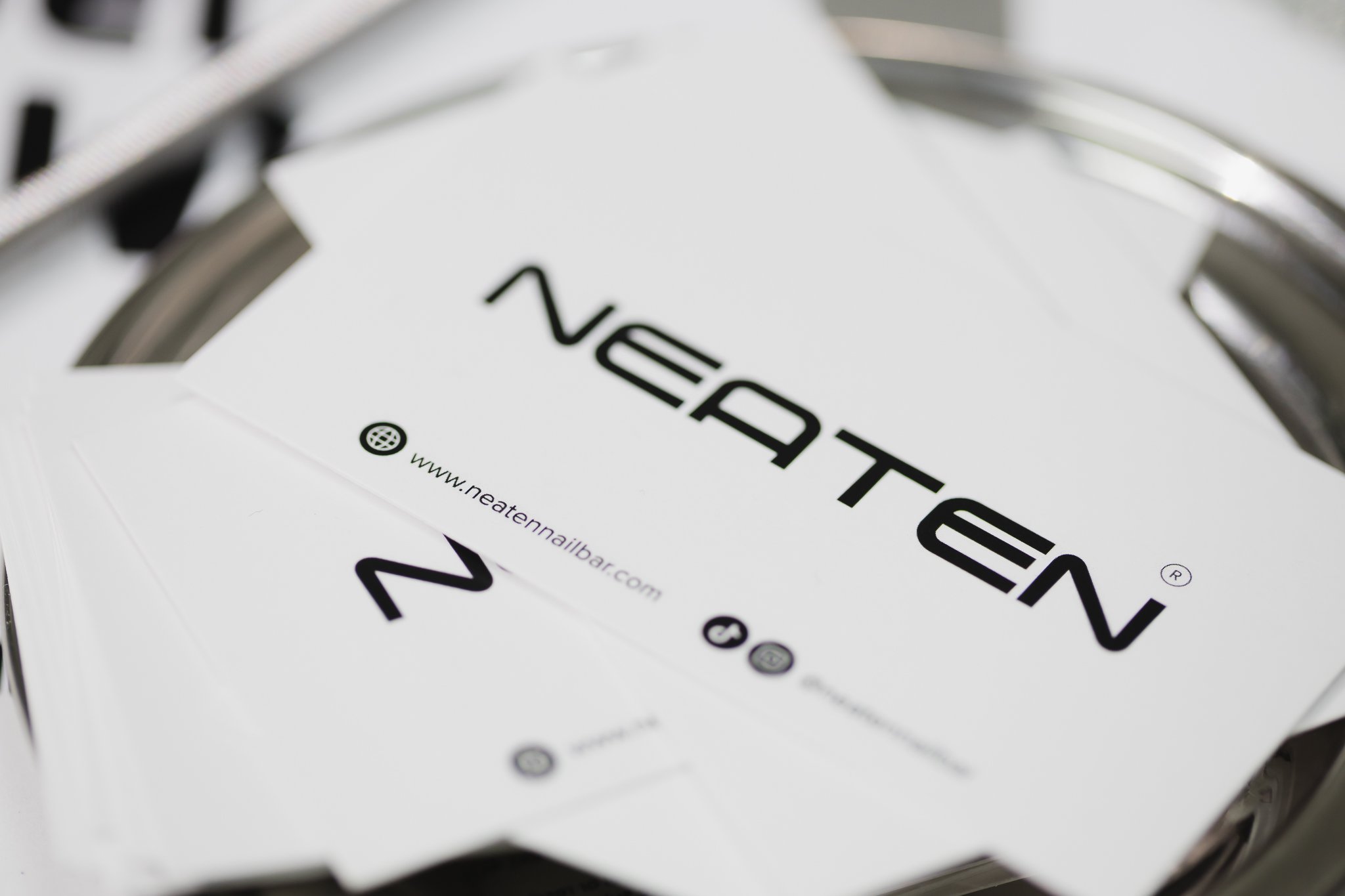 Close-up of a white sheet with black text and symbols about nail bar services, placed on a metallic surface.